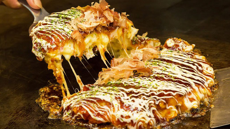 alt text: Bánh xèo Okonomiyaki trên bàn nướng Teppan