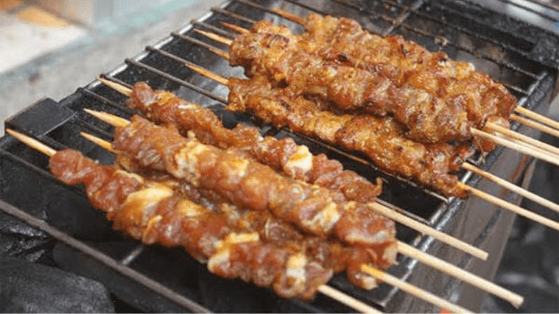 alt text: Lợn đồi nướng xiên Tam Đảo, món ăn đường phố hấp dẫn với thịt lợn nướng thơm lừng, chấm cùng nước sốt đậm đà.