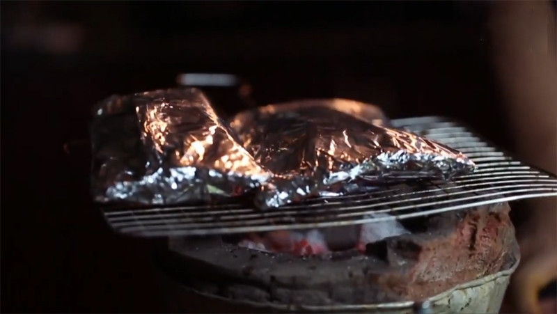 alt text: Nướng cá đuối trên bếp than hồng cho đến khi cá chín vàng đều các mặt.